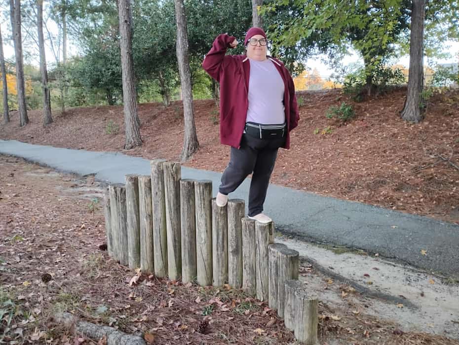 Woman balancing on a log balancing obstacle. 